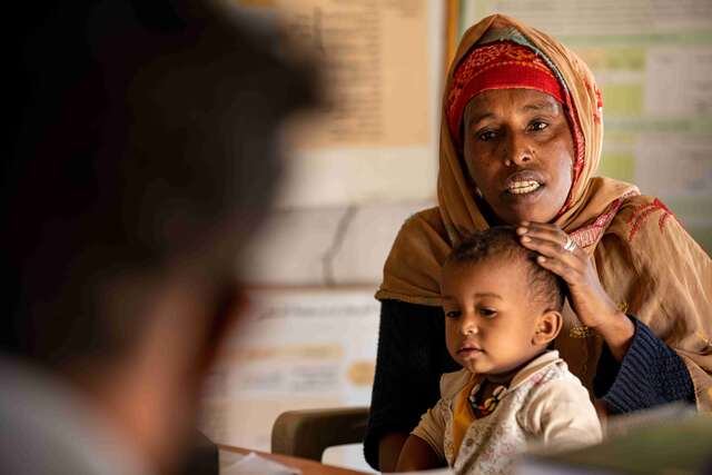 A doctor consults with a client and her child, assisted by a translator, at the IRC medical clinic supported by the European Union in Gedaref, Sudan.